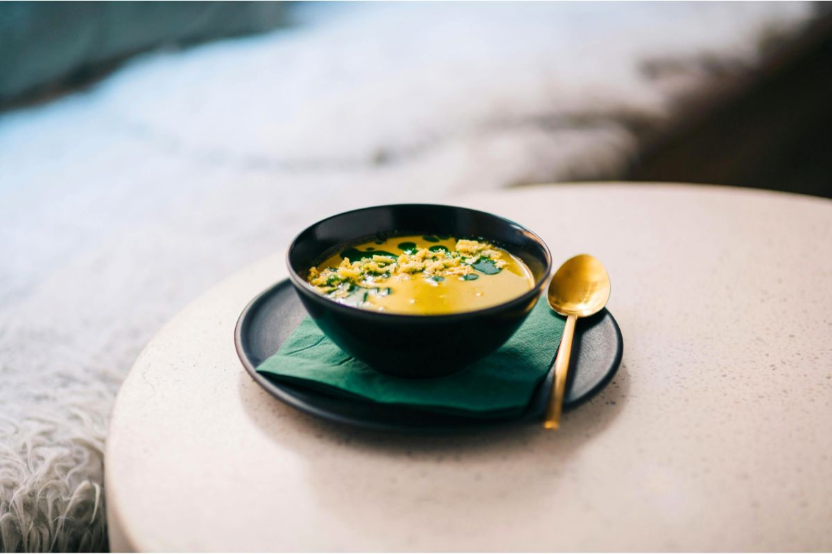 Creamy butternut squash soup in white ceramic bowl with wooden spoon,  and herb garnish - cozy fall food photography