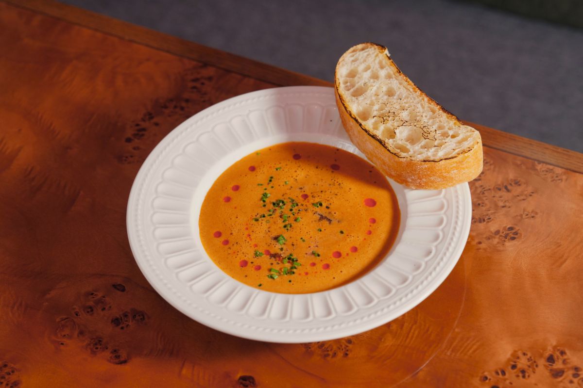 Butternut squash soup served with rustic bread, herbs and wooden spoon - cozy fall dinner table setting for family meals