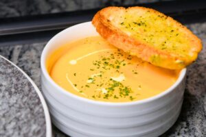 Creamy roasted butternut squash soup in white bowl with apple cider croutons and fresh herbs - easy 30-minute fall recipe