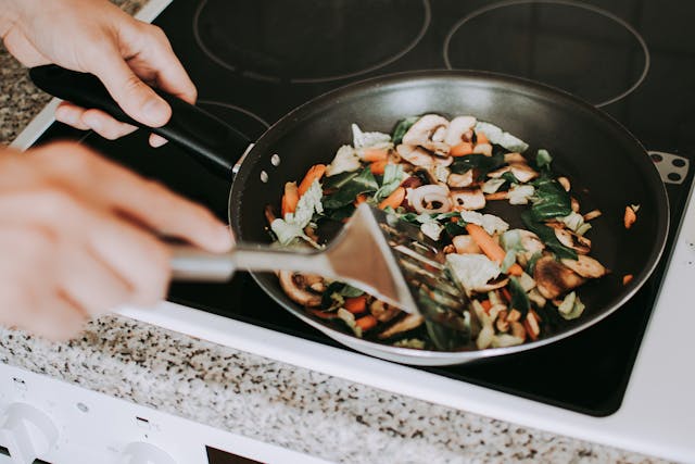 Quick honey garlic chicken stir-fry cooking in skillet with broccoli and peppers