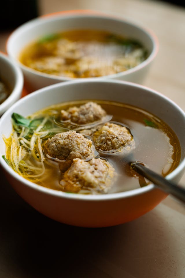Close-up of Italian wedding soup with tiny meatballs, spinach, and acini di pepe pasta in rich broth