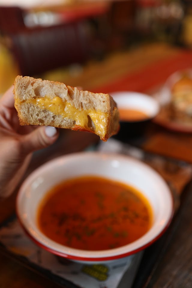 Crispy golden brown grilled cheese sandwiches cut into dipping strips, served beside a bowl of tomato soup
