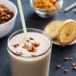 Creamy banana date smoothie in glass with cinnamon dust and straw - healthy no-sugar breakfast drink