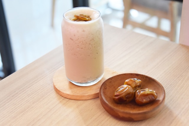 Banana date smoothie served in glass with straw and cinnamon garnish - ready to drink healthy breakfast shake