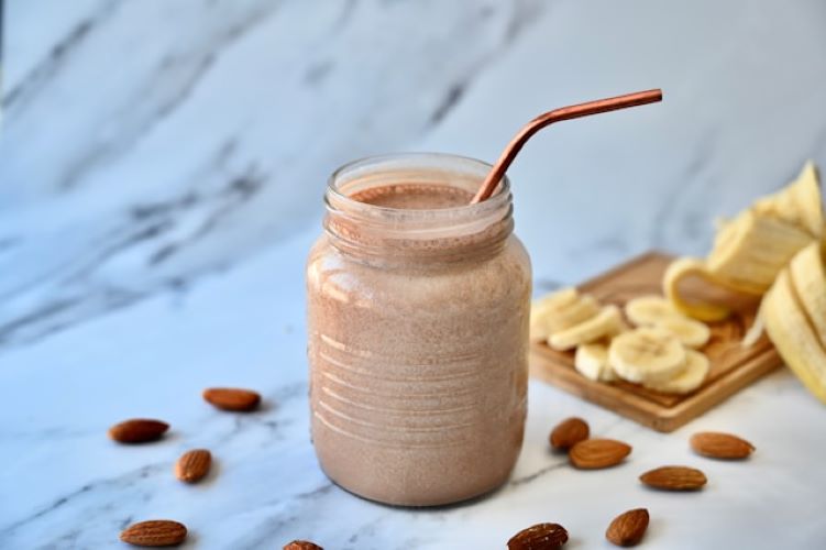 Creamy banana date smoothie in glass with cinnamon dust and straw - healthy no-sugar breakfast drink