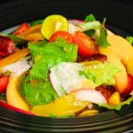 Grilled peach salad with burrata, prosciutto, and arugula on white platter - quick healthy summer recipe