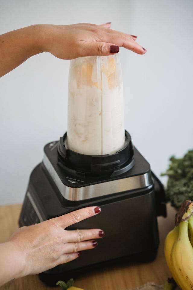 Blending mango date smoothie in high-speed blender with frozen mango and plant-based milk - creamy texture forming