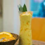Creamy mango date smoothie in glass with straw and cinnamon dust - healthy no-sugar tropical drink