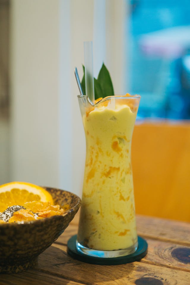 Creamy mango date smoothie in glass with straw and cinnamon dust - healthy no-sugar tropical drink