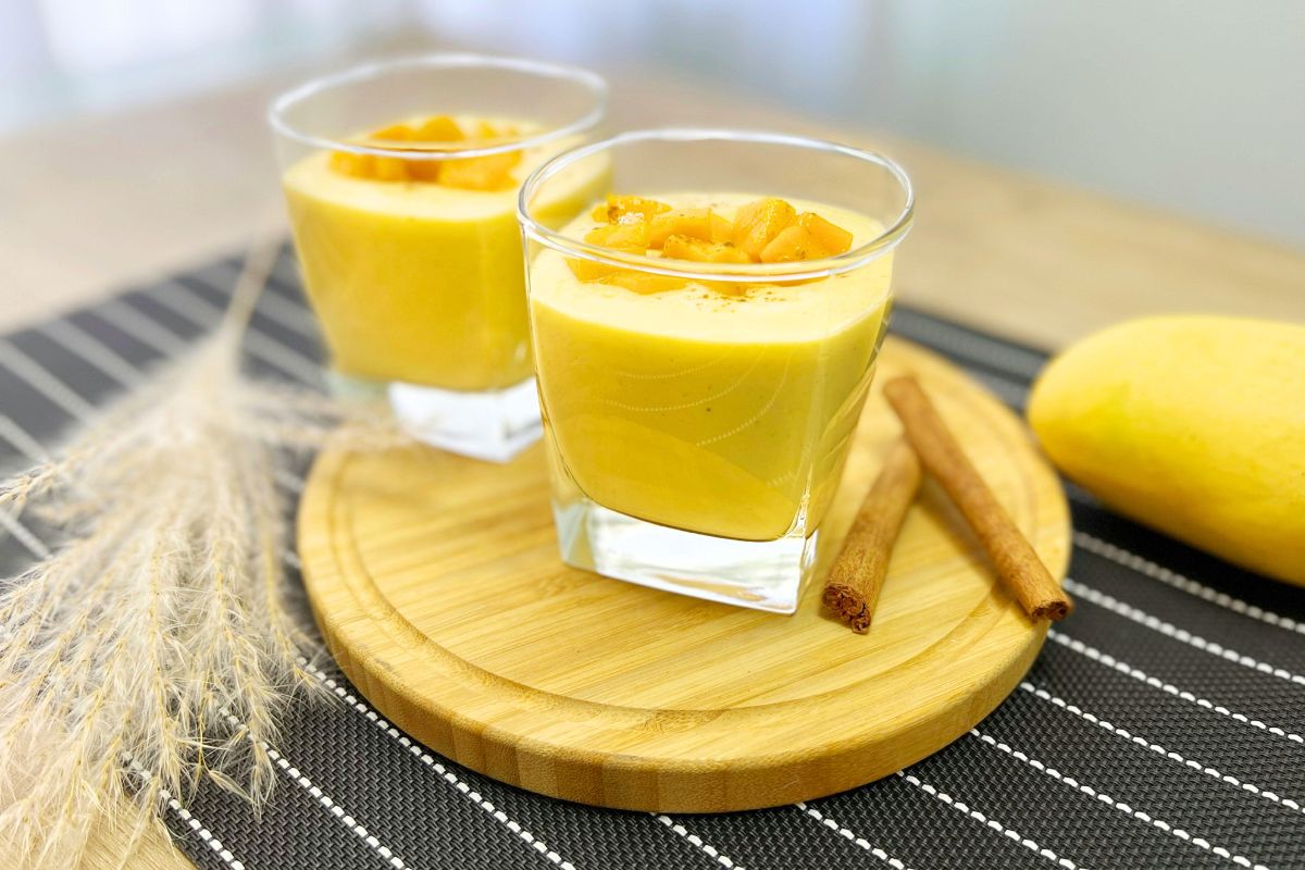 Mango date smoothie in tall glass with straw - ready to drink vegan breakfast shake