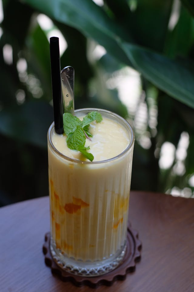 Homemade mango lassi served in traditional glass with mint garnish