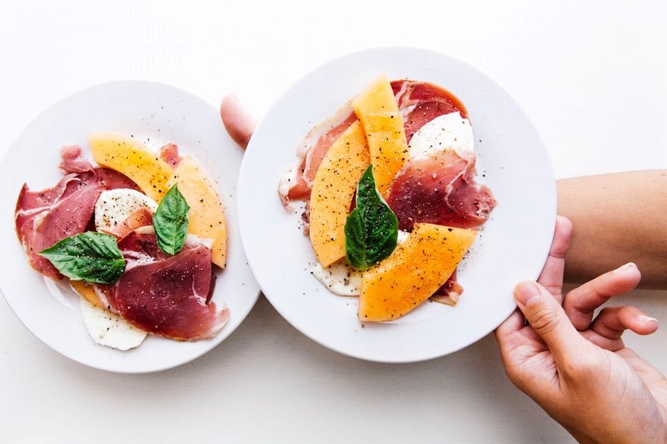 Plated grilled peach salad with creamy burrata, prosciutto, and fresh arugula - elegant summer dish