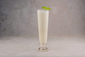 creamy sweet lassi in a glass topped with froth