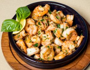 Easy homemade shrimp scampi in a cast iron skillet, featuring juicy shrimp, garlic, lemon slices, and fresh herbs.