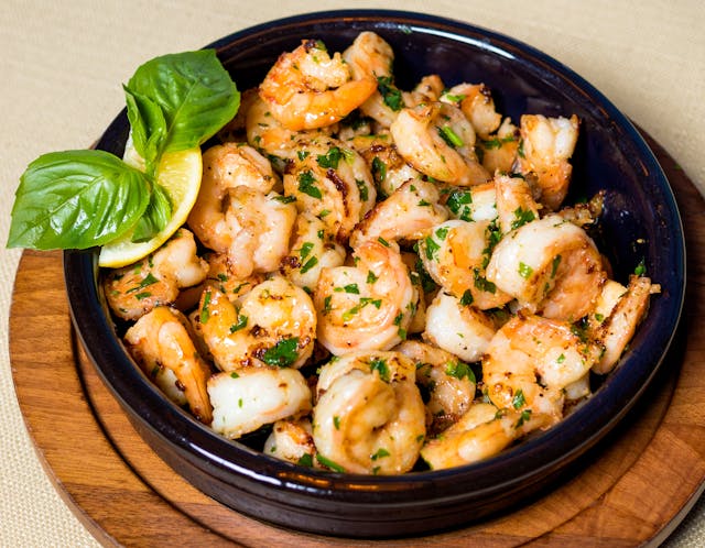 Easy homemade shrimp scampi in a cast iron skillet, featuring juicy shrimp, garlic, lemon slices, and fresh herbs.