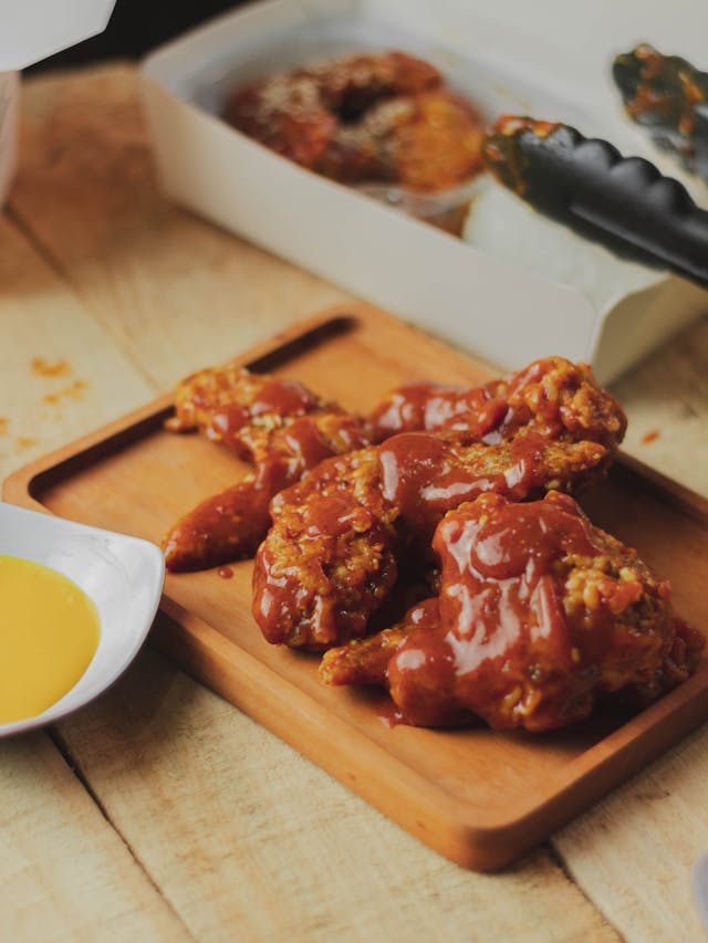 Juicy grilled chicken wings glazed with hot honey BBQ sauce, garnished with green onions
